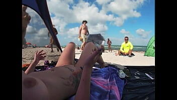 EW 511 - Mi esposo filma a la Sra. Kandii Kiss y nos muestra cómo se ven los mirones jugando con sus pollas cuando ella se tumba en la playa nudista con las piernas abiertas para que todos la vean.